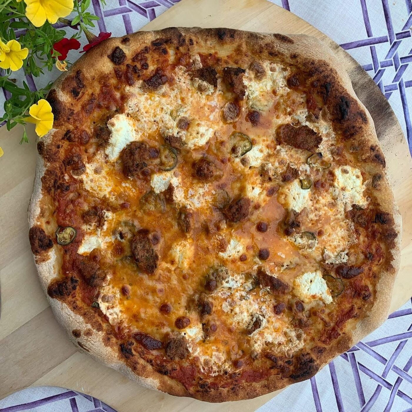 Artisan pizza on checkered cloth with flowers — private chef catering